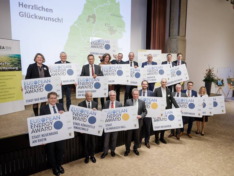 Eine Gruppe von Menschen präsentiert europäische Energiepreise auf einer Bühne, vor einer Karte und einem "Herzlichen Glückwunsch!"-Schriftzug.