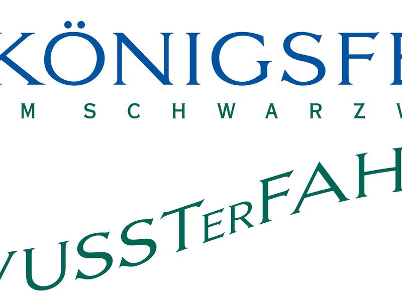 Das Bild zeigt das Logo von Königsfeld im Schwarzwald mit einem stilisierten Gebäude und dem Slogan "Bewusster fahren".