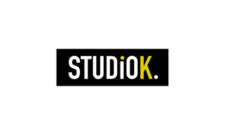 StudioK Königsfeld Logo. Weiße Schrift mit StudioK. Das K am Ende ist in einem schönen gelbton gesetzt.